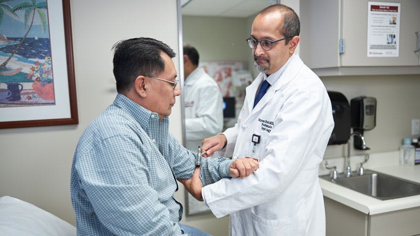 Stroke expert Shyam Prabhakaran, MD, MS with a male stroke patient in a doctors office