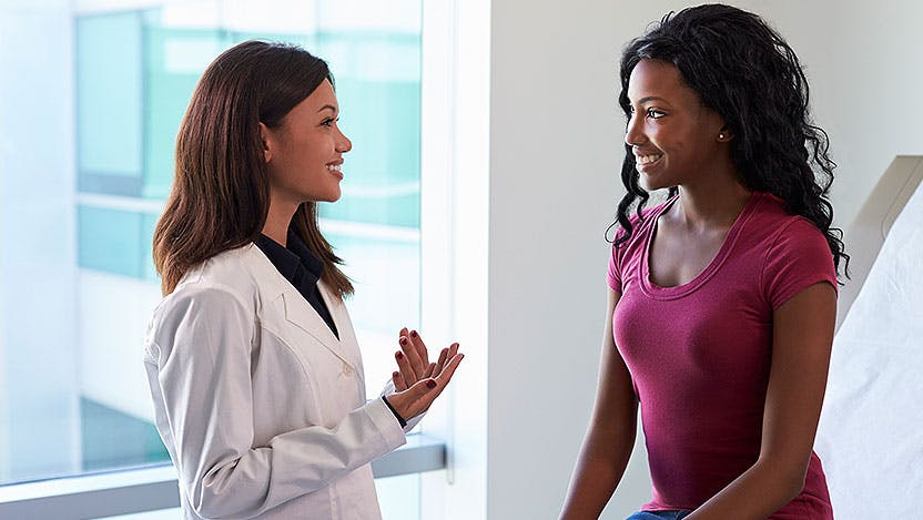 Doctor speaks with black female patient in exam room