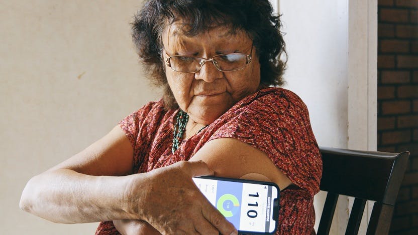 an older navajo woman checks her blood glucose with a smartphone app