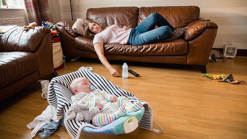 Mom napping on couch while newborn naps in sleeper