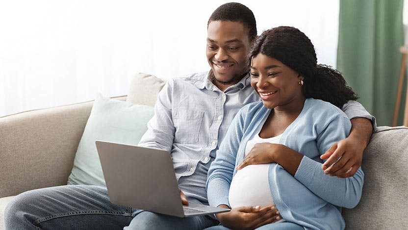 Smiling pregnant couple taking an online prenatal class