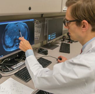 Xavier Keutgen, MD, pointing at scan on computer monitor