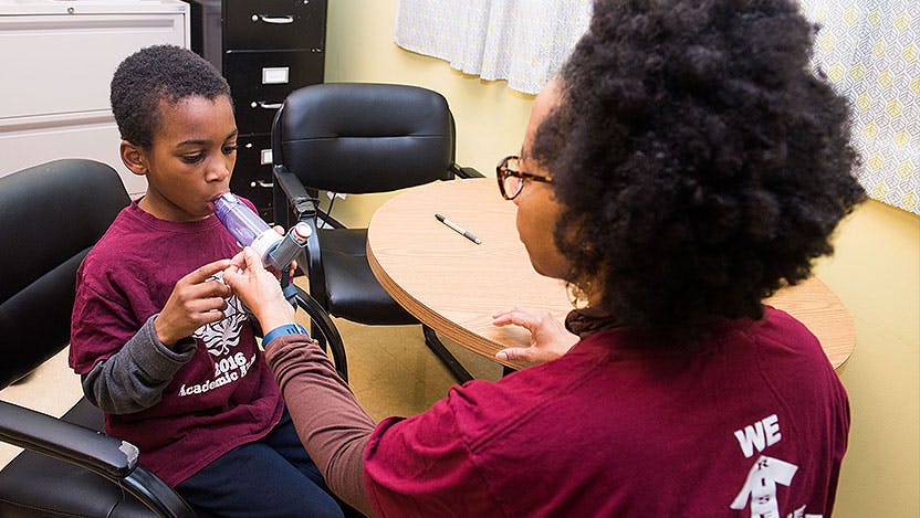 Nurse coaches pediatric asthma patient on proper inhaler use