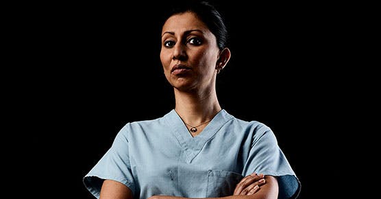 Anjana Pillai, MD, in a white coat with her arms crossed facing the camera