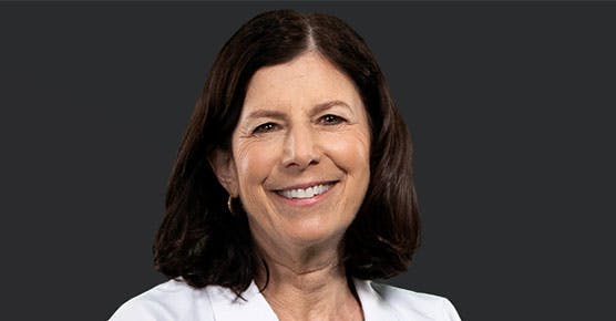 Susan Cohn, MD, in a white coat facing the camera against a black background