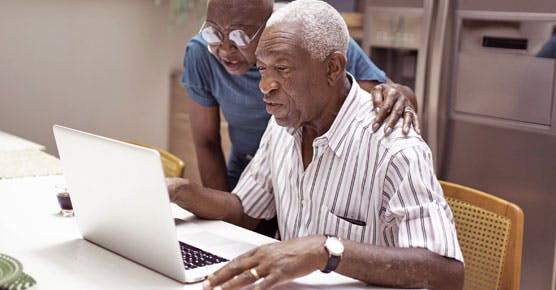 older man and woman at home, looking at laptop screen