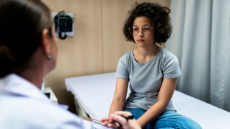 Girl on clinic bed talking with doctor